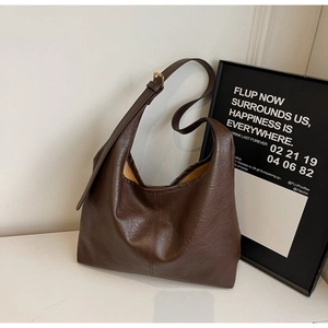 Detail of vintage dark brown tote bag showing wrinkled PU leather and gold metal buckle