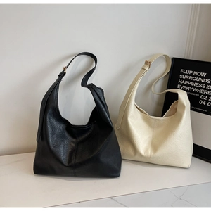 Detailed view of textured lychee grain faux leather on tote bags with adjustable gold buckles