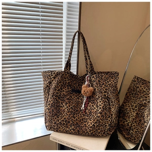 Leoparden-Tote-Bag aus Canvas mit Teddybär-Anhänger auf weißen Büchern im Detail