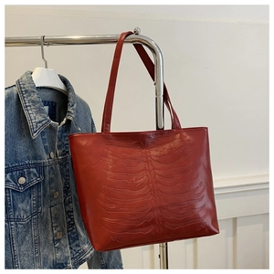 Detail of red tote bag with gothic rib cage relief design and crocodile texture PU