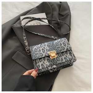 Detailed view of leopard print flap bag with gold metal buckle on a grey blazer