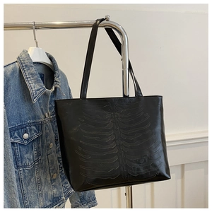 Detail of black faux leather tote bag featuring a 3D embossed skeletal rib cage pattern