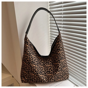 Close-up of leopard print shoulder bag with black leather handle in soft window light