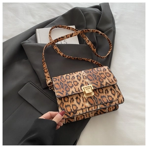 Detail of trendy leopard print handbag featuring a gold buckle on grey blazer