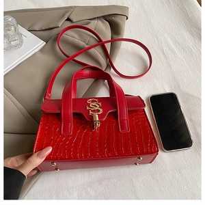 Detail of red crocodile texture handbag featuring golden SS metal lock and hardware