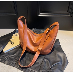 Detail view of brown vintage crescent bag on leather jacket with artistic book accent
