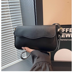 Detail shot of the wavy flap closure and matte black texture on a stylish handbag
