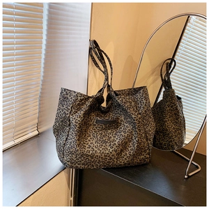 Detail of large leopard print canvas tote bag with slim shoulder straps and leather patch
