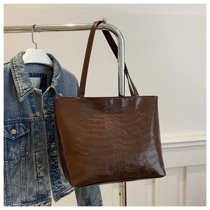 Detail view of large brown tote bag with unique embossed rib cage bone pattern