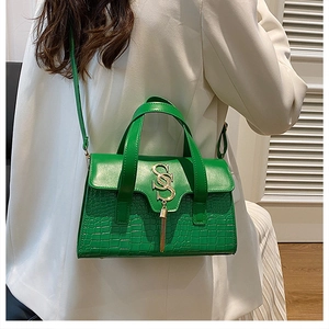 Detail of green faux leather handbag with gold SS logo and crocodile pattern texture
