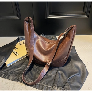 Detail of a brown hobo bag in glossy vintage leather with adjustable strap and metal hardware