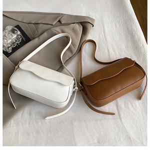 Detail of cream and caramel shoulder bags with wavy flap design on textured fabric