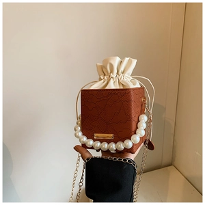 Detail of vintage square bag with brown lace texture, pearl handle, and drawstring