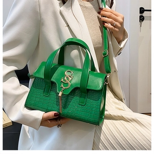 Detail of bright green crossbody bag with snake texture and metallic S-pendant