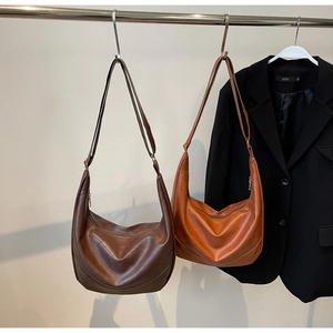 Detail of retro leather hobo bags in dark brown and caramel with adjustable straps