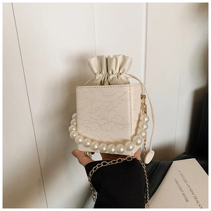 Detail of floral lace embossed square box bag with pearl handle and golden chain