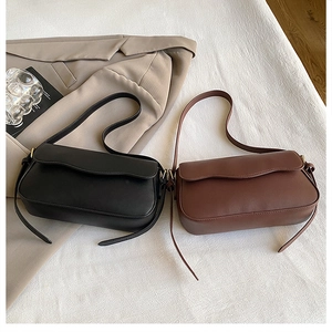 Detail view of minimalist matte leather baguette bags with magnetic flaps and gold hardware
