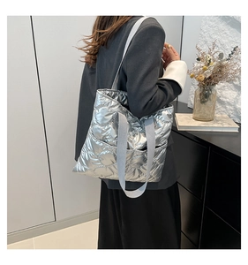 Silver quilted padded tote bag shown as a shoulder bag on a model in a modern office set