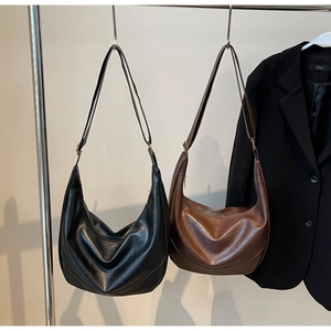 Detail view of large retro black and brown leather hobo shoulder bags with gold buckles