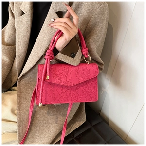 Detail of rose pink handbag with lace floral embossing and knot handle decoration
