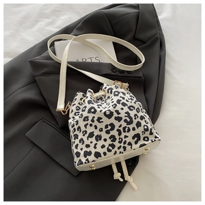 Detail of leopard print bucket bag with gold studs on white base and drawstring closure