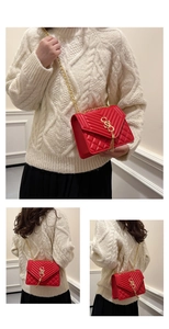 Détail d'un sac matelassé rouge avec des franges dorées et une bandoulière chaîne
