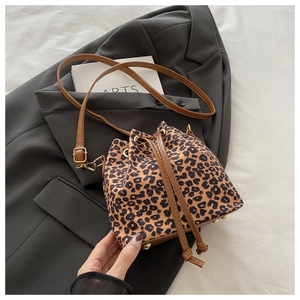Detailed close-up of leopard print bucket bag with leather strap and metal bottom feet