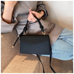 Detail of black faux leather bag featuring floral lace texture and knotted handle rings