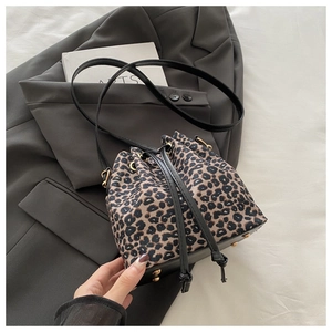 Close-up of leopard bucket bag showing metal rivets and drawstring on grey fabric