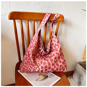 Detailed view of pink leopard print canvas tote bag hanging on a vintage wooden chair
