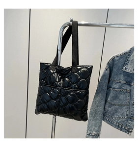 Close-up of black quilted tote bag with shiny high-density fabric and wide straps