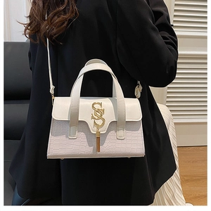 Detail of white crocodile embossed crossbody bag with golden S logo on black blazer