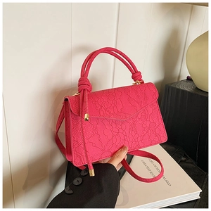 Detail of hot pink handbag featuring lace embossed texture and braided top handle