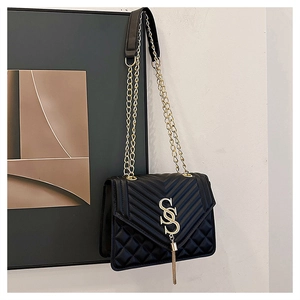 Détail du sac bandoulière noir matelassé avec logo S doré et pompon en métal élégant