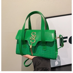 Detail of bright green crocodile embossed handbag with gold SSS letter hardware