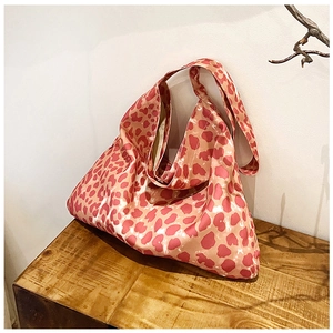 Detail of soft leopard print tote bag with wide strap on minimalist wooden background