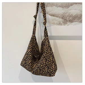 Nahaufnahme der hobo-tasche mit Leopardenmuster und geknotetem Riemen an weißer Wand