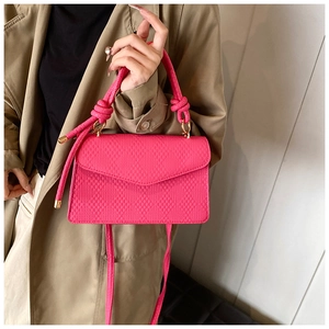 Détail d'un sac bandoulière matelassé rose rouge avec poignée et finitions dorées