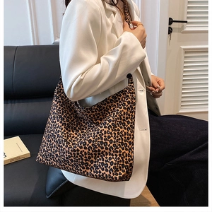 Detailed view of the leopard print canvas hobo bag worn by a model in a casual setting