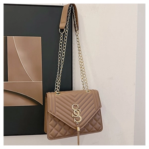 Détail du sac bandoulière matelassé marron avec chaîne dorée et pompon à lettre S