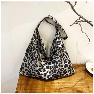 Close-up of leopard print canvas tote bag with wide strap on minimalist wooden table