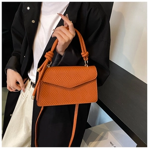Sac bandoulière orange texturé avec poignée nouée porté avec un blazer noir chic