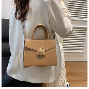 Detailed view of women beige leather handbag with gold flower clasp on a model shoulder