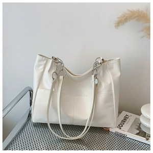 Détail du grand sac cabas blanc avec anneaux en chaîne argentée et poches avant pratiques