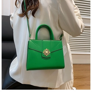 Detail of a vibrant green crossbody bag with a gold decorative rotating metal buckle