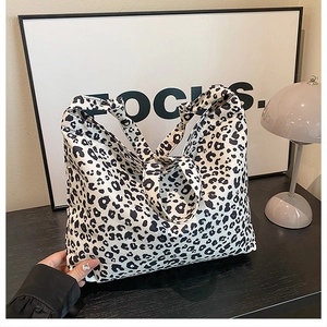 Close-up of black and white leopard print canvas tote bag with wide strap and metal buckle