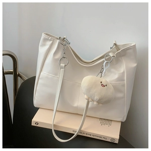 Détail d'un sac cabas en cuir blanc avec chaîne argentée et breloque peluche