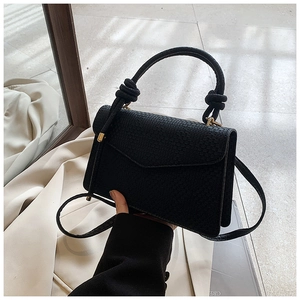 Détail de la texture tressée noire et de la poignée nouée sur un petit sac carré