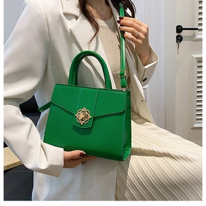 Detail of emerald green handbag featuring a gold floral buckle and fine leather texture
