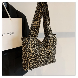 Detail of leopard print canvas tote bag hanging next to a suit for casual style